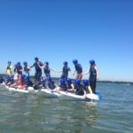 students balancing whilst standing up on kayaks