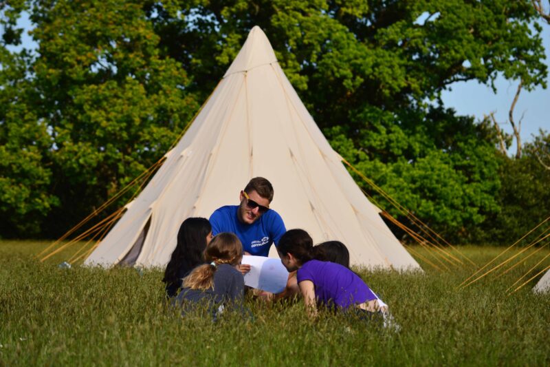 Cumulus instructor and three pupils reading outside a tipi