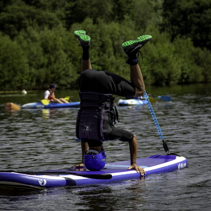 boy head stand on stand up paddleboard dorset