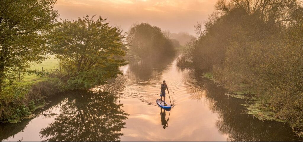 boy stand up paddleboarding on river in Dorset cumulus outdoors