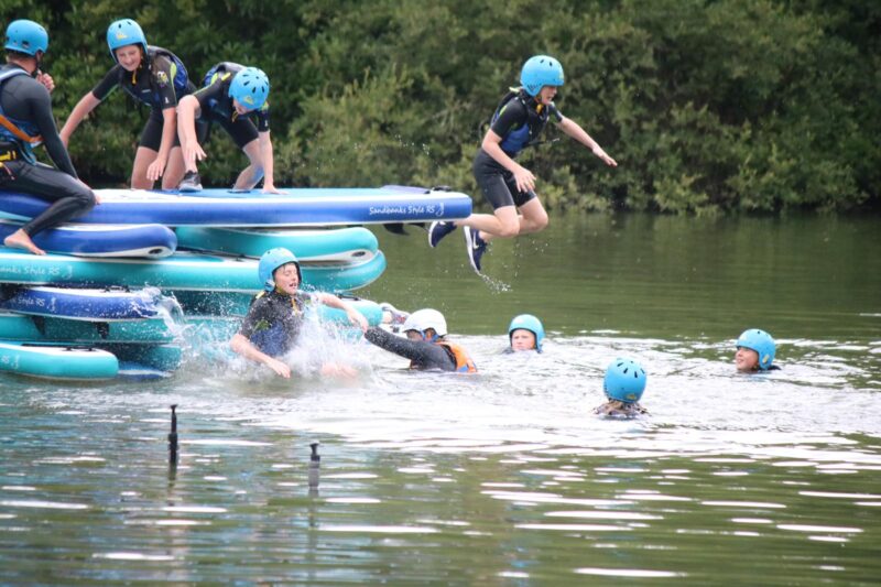 children jumping from stand up paddleboards