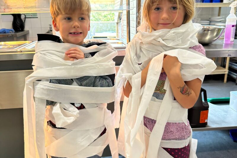 two children wrapped as mummies during Halloween activity club