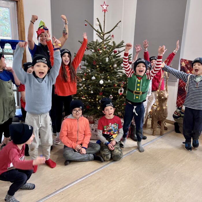 children cheering next to christmas tree