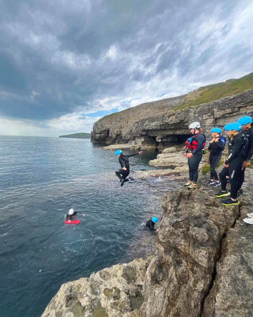 students jumping off the Dancing Ledge in Dorset during a coasteering activity